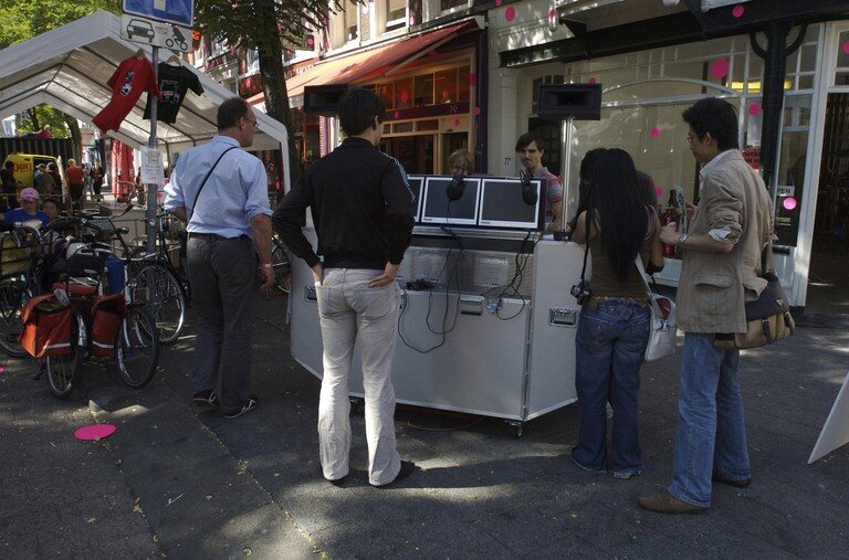 The Burn Station unit on a street, people gathered around its two screens.