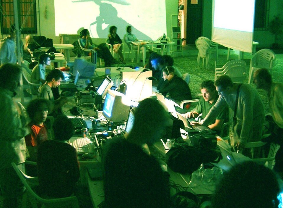 Night media lab: people working at CRT monitors and laptops under a video projection.